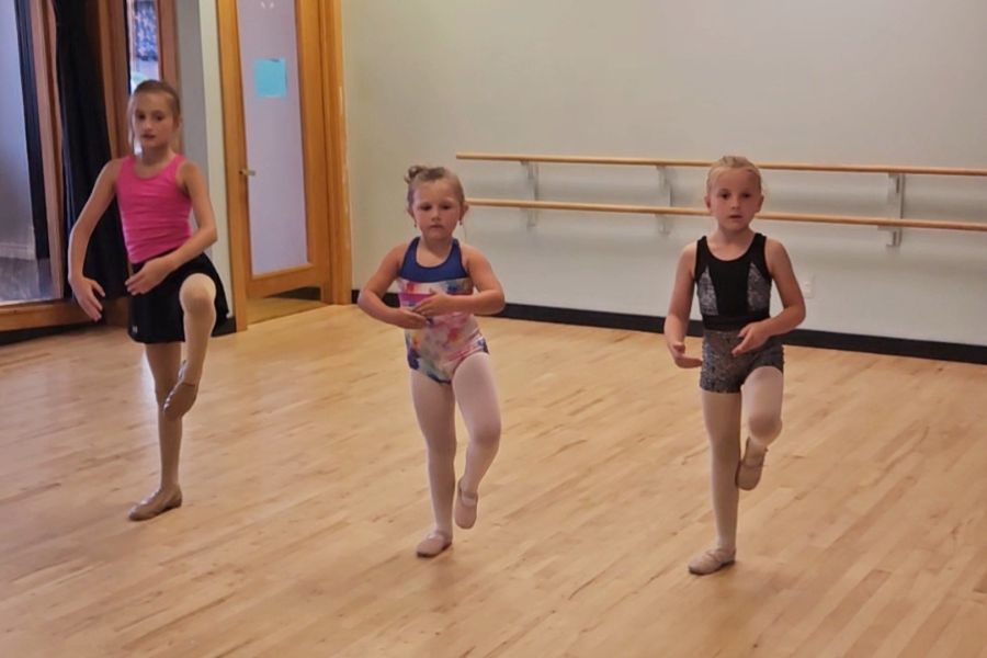 Young girls in a beginner ballet class practicing leg lifts at a dance studio in Brighton, MI